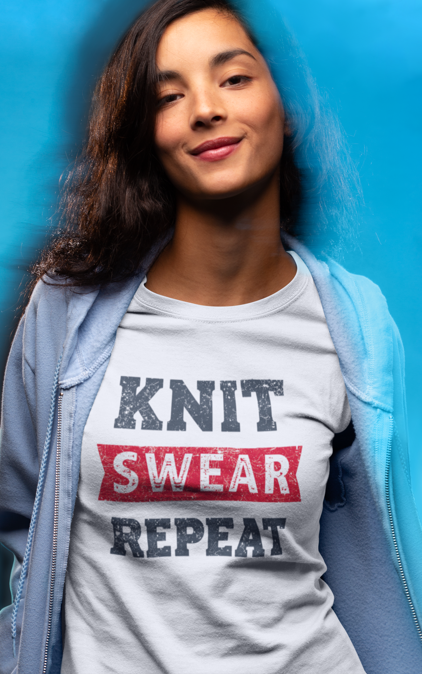 Woman wearing a t-shirt with 'KNIT SWEAR REPEAT' text against a blue background