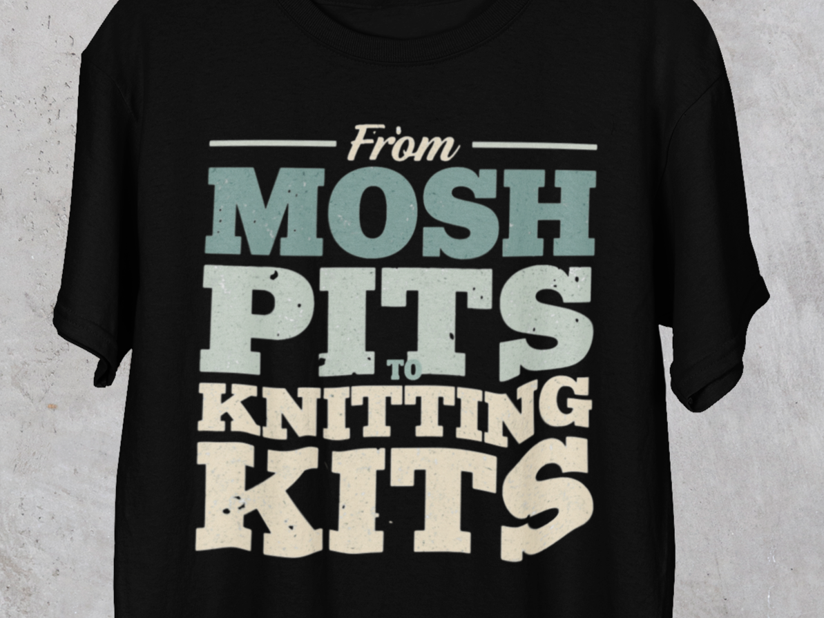 Black t-shirt with text 'From Mosh Pits to Knitting Kits' on a textured gray background
