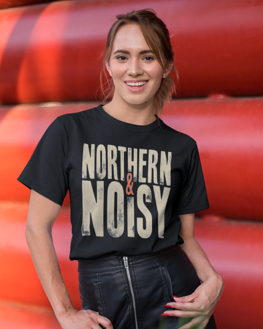 Person wearing a black t-shirt with 'Northern & Noisy' text in front of red cylindrical objects.