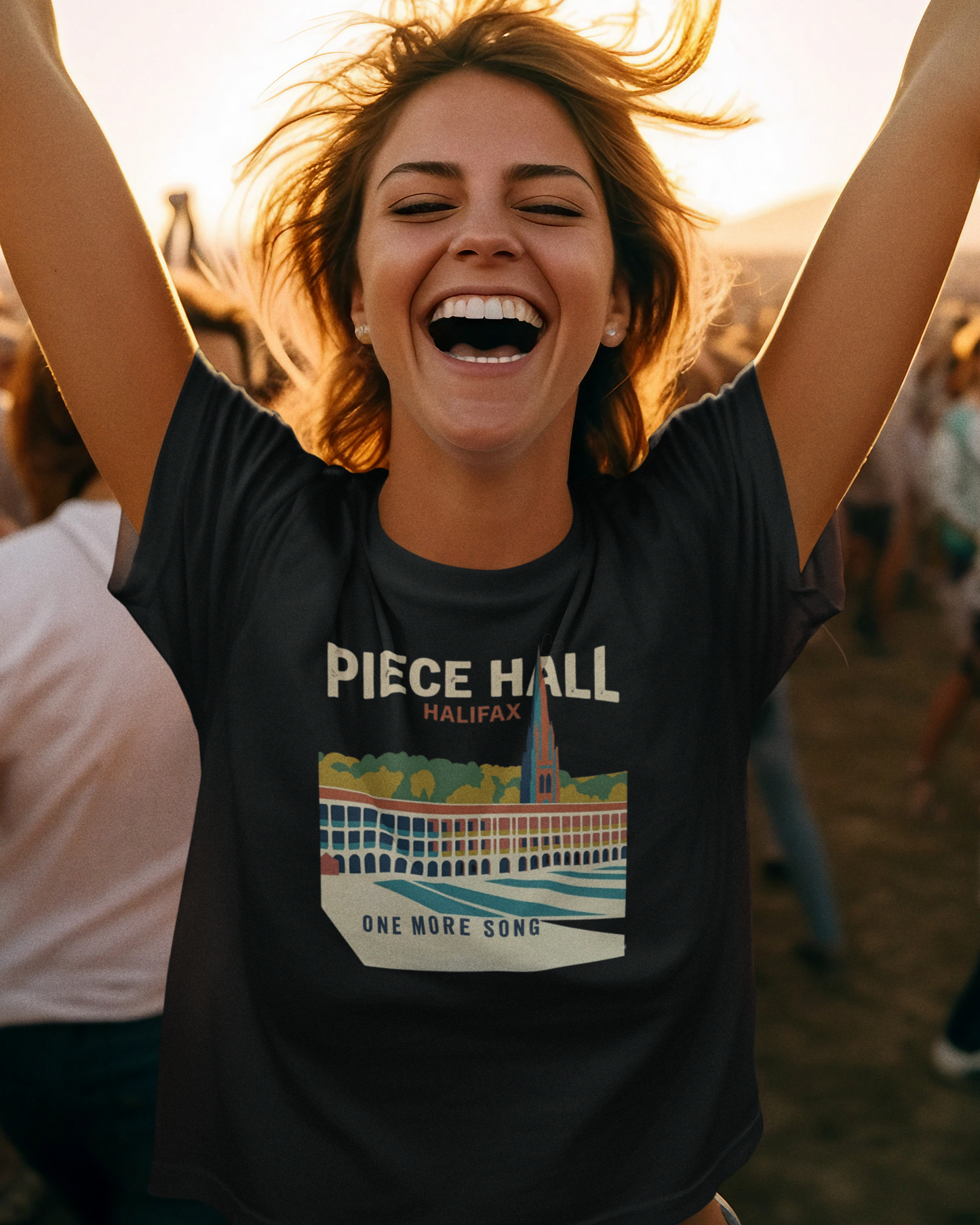 Woman wearing a 'Piece Hall Halifax' t-shirt with arms raised outdoors.