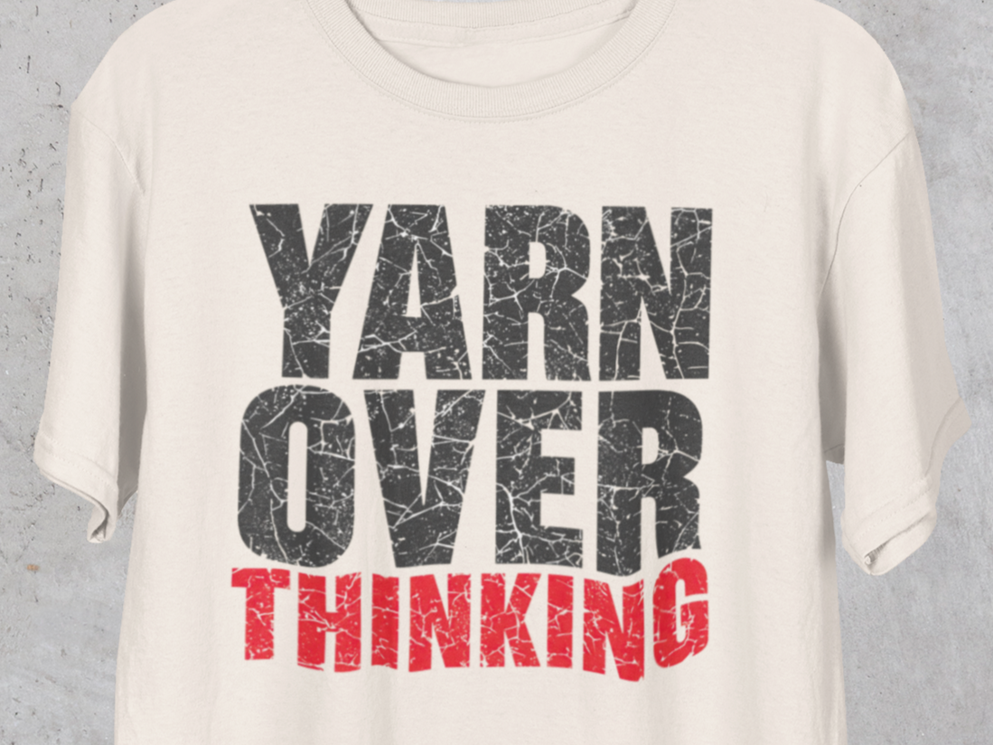 White t-shirt with 'YARN OVER THINKING' text in black and red on a gray background