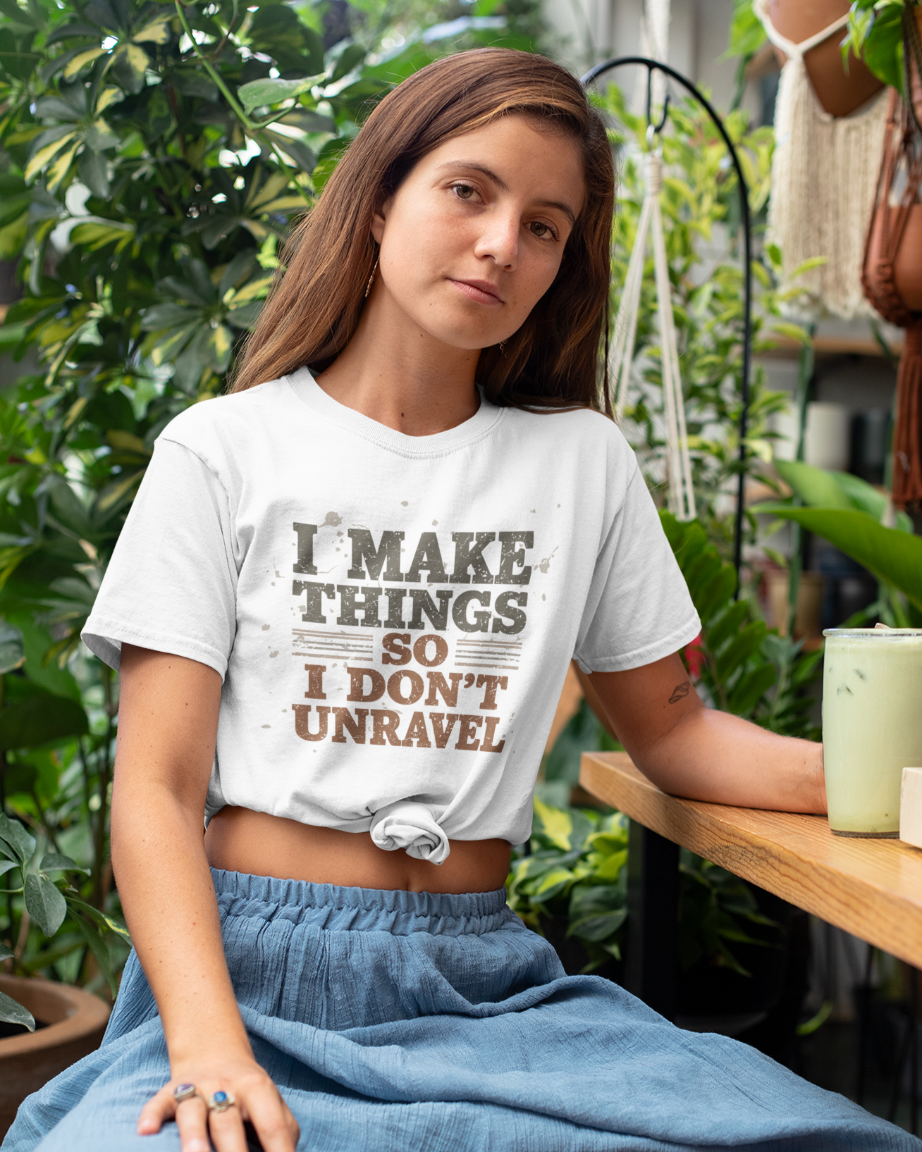 Woman wearing a white t-shirt with text sitting outdoors.